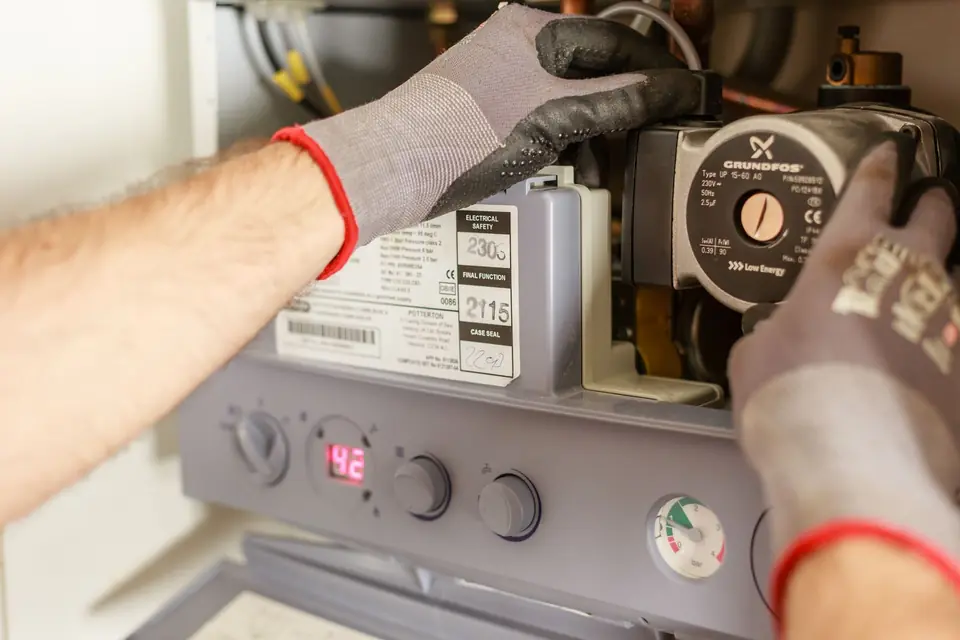 A heating engineer working on a wall-mounted gas boiler