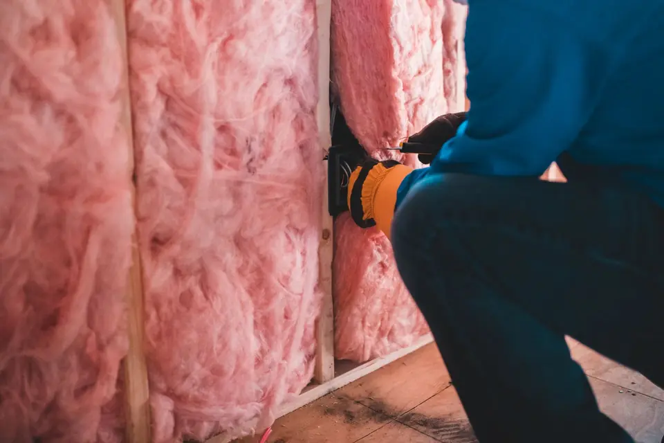Rolls of mineral wool loft insulation being laid between joists