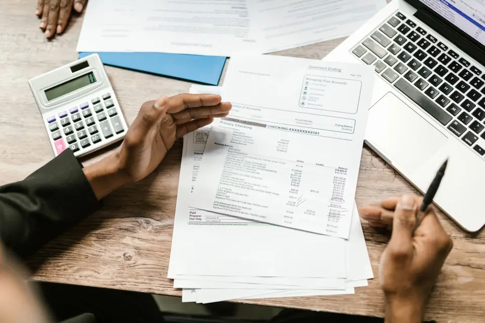 Invoices, a calculator and a laptop on a desk